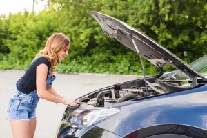 車のボンネットを開く女性